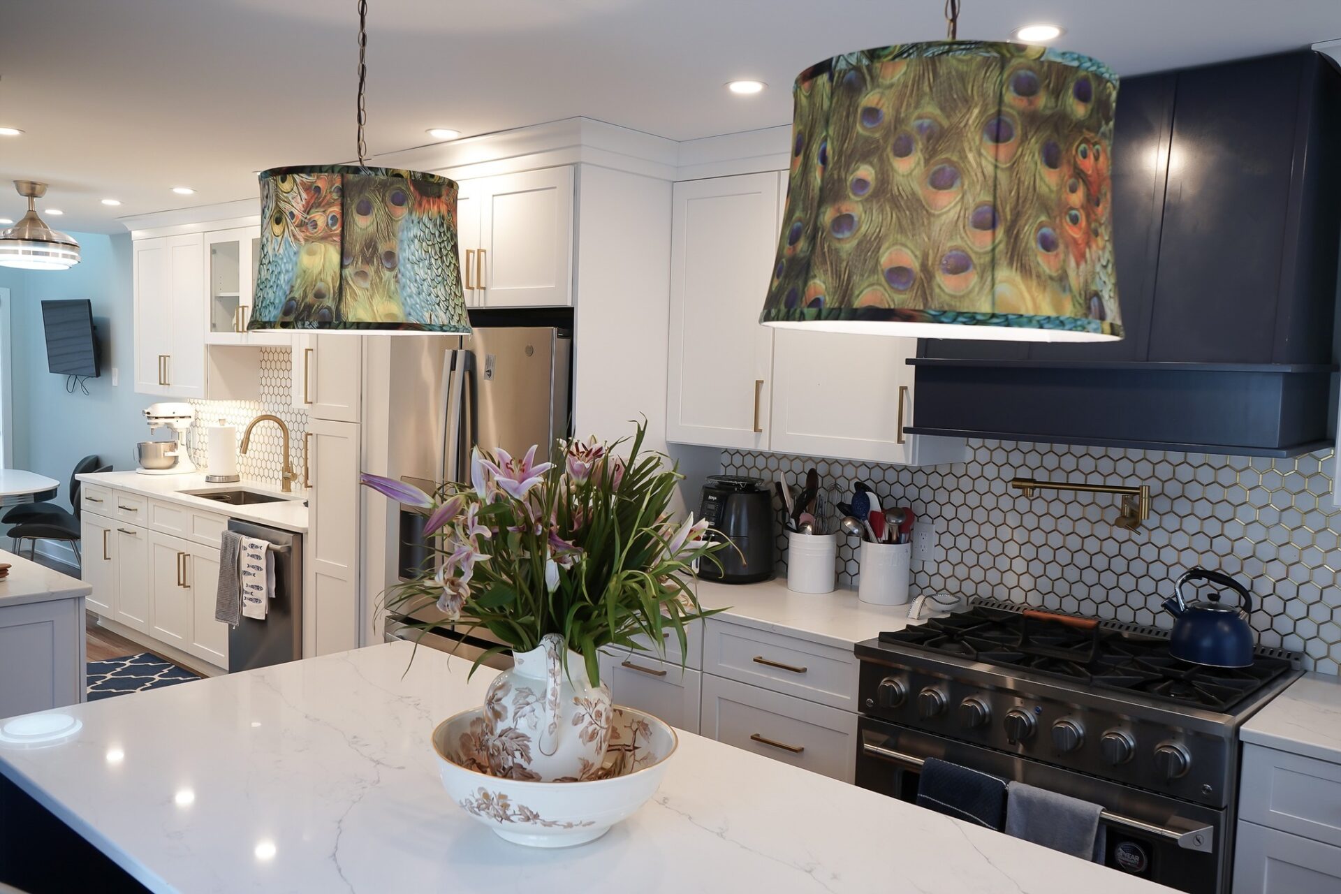 Newington Kitchen Remodel Stylish kitchen remodel in Newington, CT featuring white shaker cabinets, peacock feather pendant lights, gold hardware, and a luxury gas range with honeycomb tile backsplash.